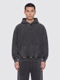 aftr99 | A man wearing a dark gray washed hoodie with a small black embroidered logo on the chest, paired with matching dark gray sweatpants, against a light gray studio background.