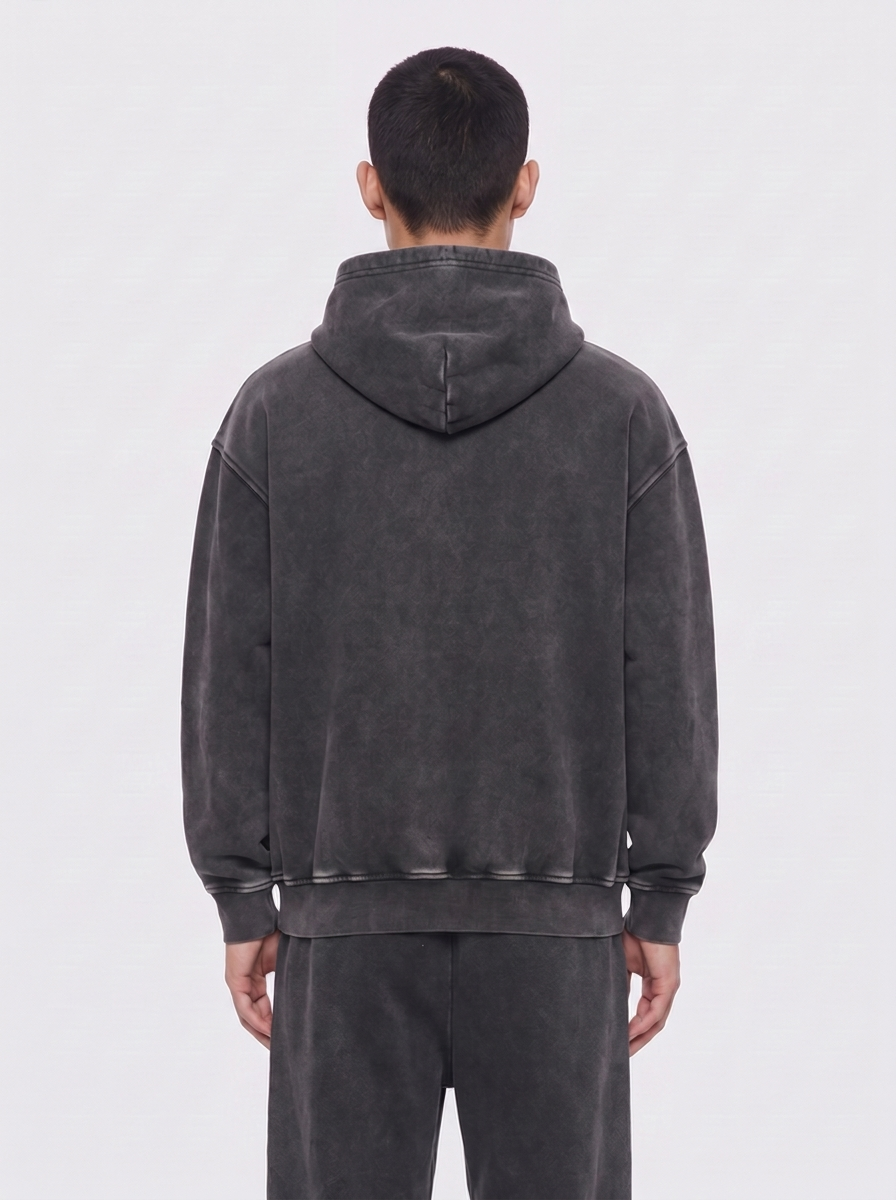 aftr99 | A man viewed from the back wearing a dark gray washed hooded sweatshirt and matching dark gray sweatpants against a light gray studio background.