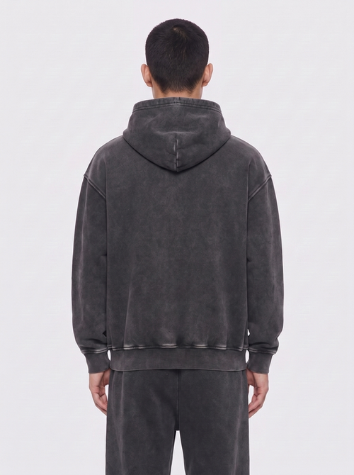 aftr99 | A man viewed from the back wearing a dark gray washed hooded sweatshirt and matching dark gray sweatpants against a light gray studio background.